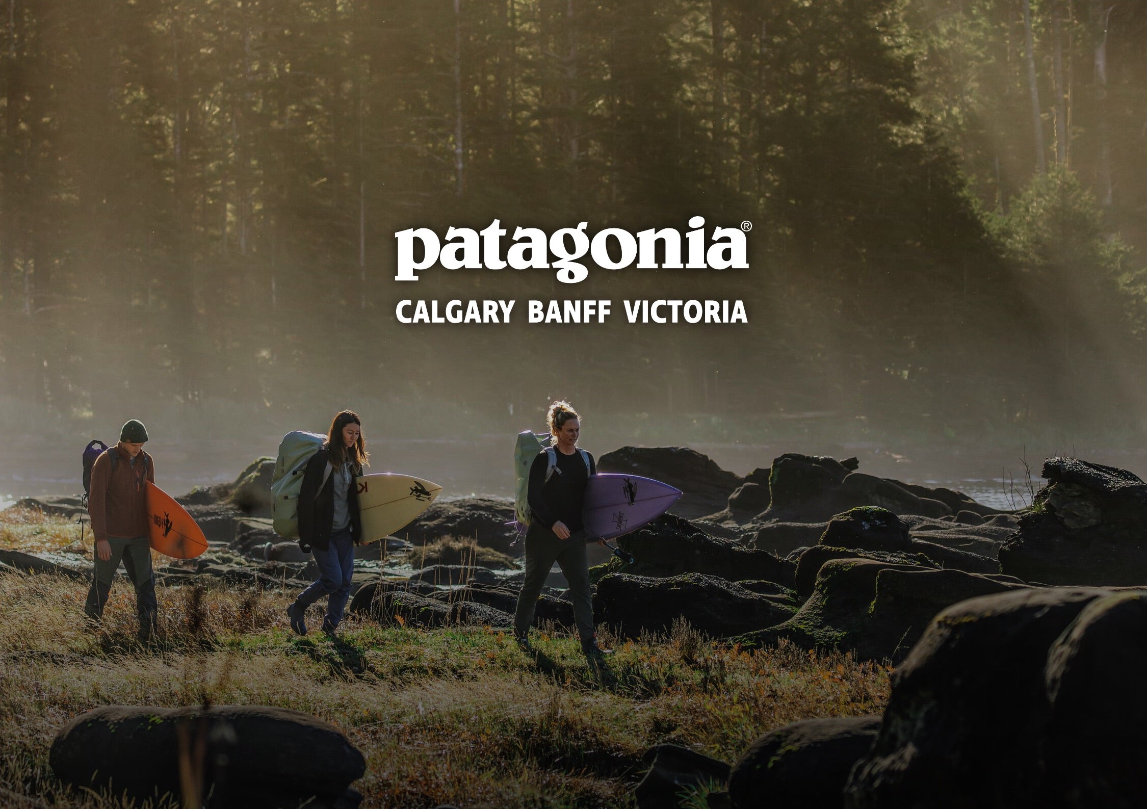Three people carrying surfboards walk along a rocky shoreline in a misty forest setting, with the Patagonia logo and text 'CALGARY BANFF VICTORIA' centered near the top.